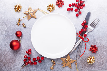 Christmas table place setting with empty white plate, cutlery with festive decorations star bow ball on stone background. Christmas and New Year holiday concept - Image