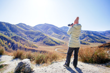 Woman hiking in mountains with camera.  Woman with a photo camera enjoys the beauty of nature...
