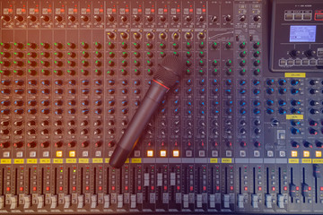 Microphone placed on the sound mixer with orange flare at the audio control room.