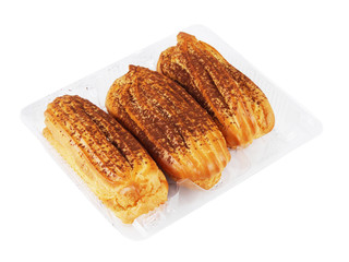 Three custard eclairs with cacao powder in a plastic container isolated on white background