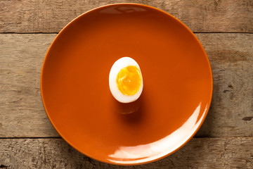 Medium-boiled eggs in a brown ceramic dish on a wooden table. Top view. Health concept.