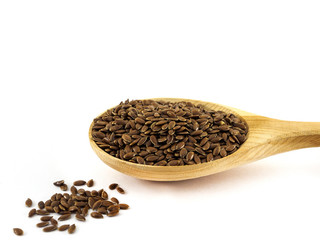 Flax seeds lie in a wooden spoon on a white background
