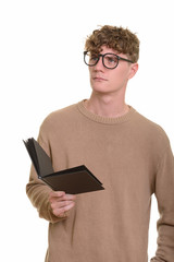 Young handsome Caucasian man thinking while holding book
