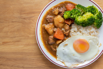 Chicken curry Rice on wooden background ( Poached egg, Potato, enoki mushroom, onion, broccoli, Japanese style,)