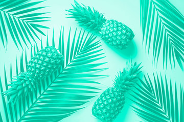Pineapple and tropical palm leaves on turquoise background. Top view. Summer concept. Creative flat...