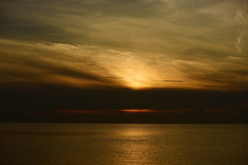 Obraz premium The view of the golden sky, the sea and a small fishing boat in the early morning, the sun is rising. 