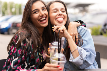 Hipster girlfriends drink cocktail in urban city background