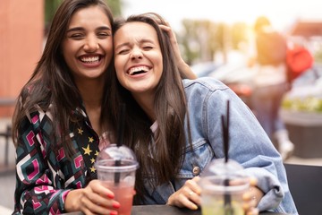 Hipster girlfriends drink cocktail in urban city background
