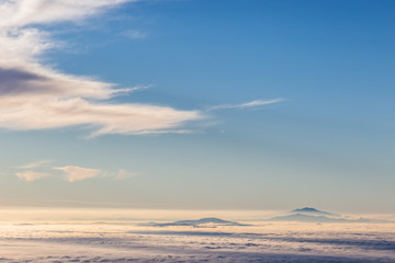 Distant mountains above a sea of fog like islands at sunset