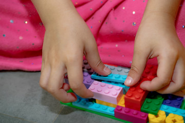 A girl is playing with colorful plastic jigsaw toys and brick sets.