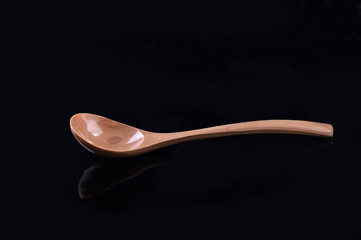 The wooden spoon on black blackground