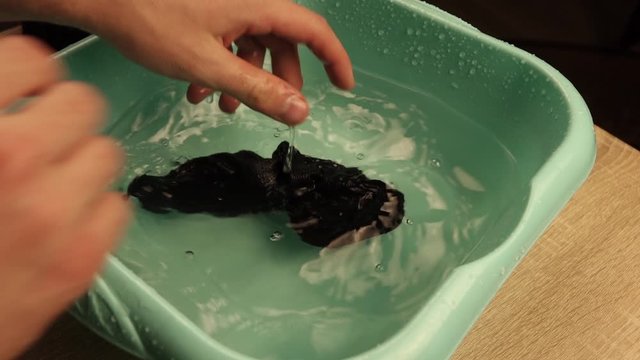 a man washes socks in a basin.