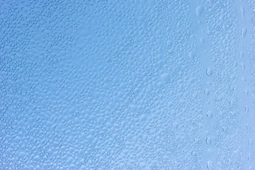 Water droplets on the glass with a blue background.
