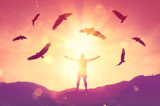 Man raise hand up on top of mountain and sunset sky with eagle birds fly abstract background.