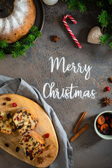 Merry Christmas text with festive decorations and Christmas fruit cake on gray background. Bakery christmas banner.