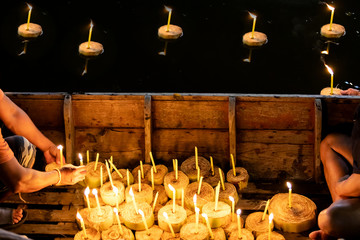 Unidentified people on the boat with burning candles at funeral ceremony. Religion and mourning concept.