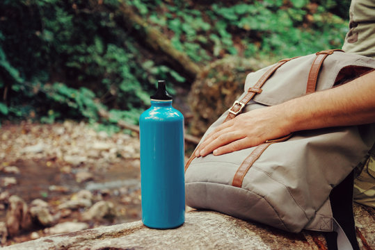 Hiker man sitting with backpack and bottle of water on nature.