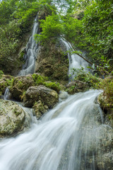 Fototapeta na wymiar Beautiful waterfall with green leaves in long exposure mode, Indonesia
