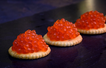 Tartlets with red caviar on dark background