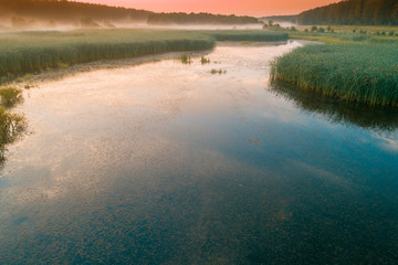 Early misty morning, sunrise over the lake. Rural landscape in summer. Aerial view