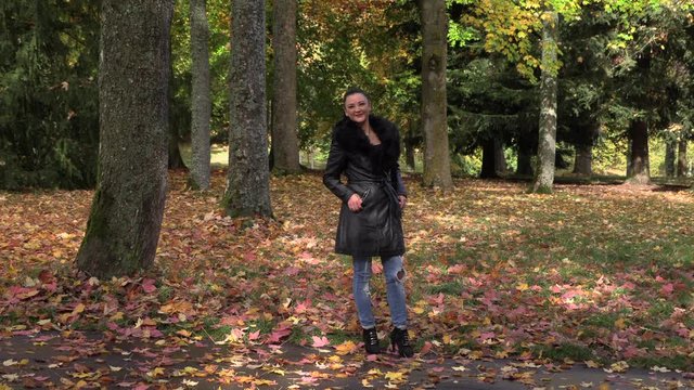 Nice girl in a black cloak in the autumn park