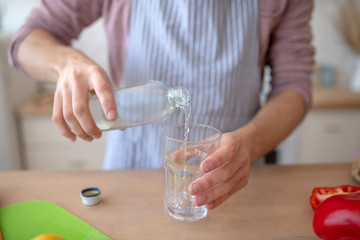 Obraz na płótnie Canvas Top view of man pouring still water into glass