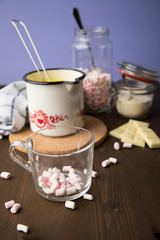Zubereitung von heißer weiße Schokolade im Milchtopf mit Kakao Pulver und Marshmallows in Küche...