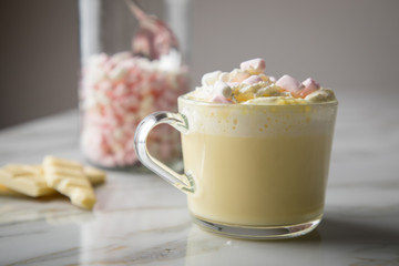 Heiße, weiße Trinkschokolade mit Sahne, Schokoladen Tafel und Marshmellows auf Marmor hell...