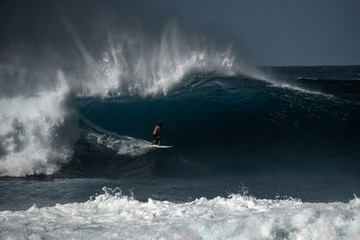 Surfer rides big wave at the famous Banzai Pipeline surf spot located on the North Shore of Oahu in Hawaii