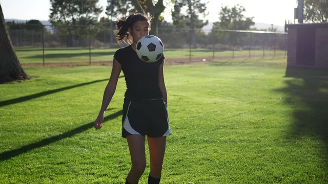 A young woman soccer player juggling and kicking a football during a team women sport practice.