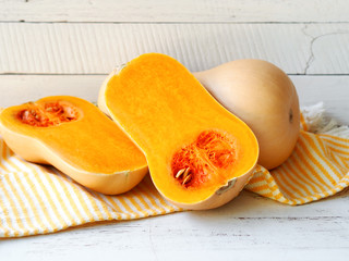 Butternut squash pumpkin cut in half   on a white color table for autumn vegetable harvest.