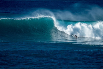 Surfer rides giant wave at the famous Waimea Bay surf spot located on the North Shore of Oahu in Hawaii - Powered by Adobe