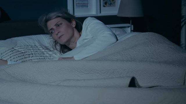 Young woman asleep at night when the phone suddenly rings and she receives bad news from someone important