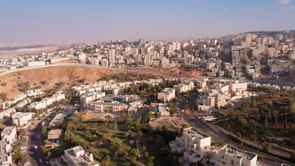 Fototapeta premium Wide Aerial footage of Israel and Palestine town divided by fence with Judean desert mountains 