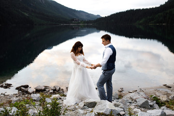 Cute young loving couple spending time in the mountains near the lake. A couple of newlyweds walk up alone. Honeymoon