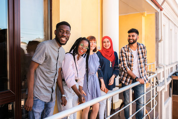 Multiracial young friends posing at the balcony of cafe. They laughing and having fun together.
