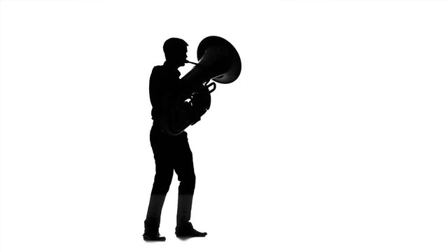 Man musician playing on tuba in slow motion. Black silhouette