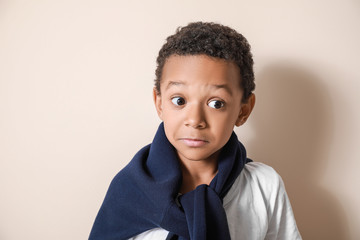 Surprised African-American boy on light background