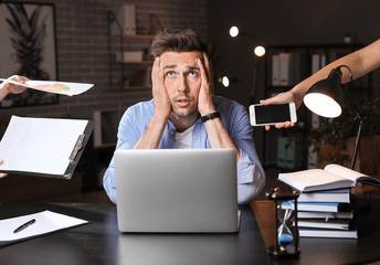 Young man with a lot of work trying to meet deadline in office