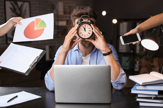 Young Man With A Lot Of Work Trying To Meet Deadline In Office