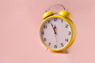 Yellow Retro style alarm clock on pink background.