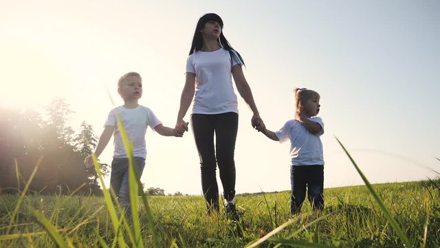 happy family funny walking go for are hold hands a teamwork Silhouette. happy children little boy and girl with mother family at sunset. mom and son mom daughter and lifestyle son in white t-shirts