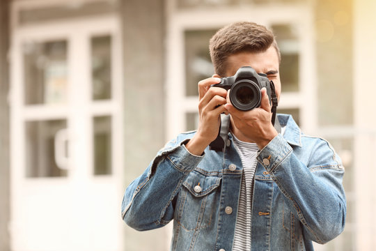 Young male photographer with camera outdoors