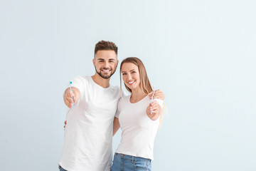 Portrait of young couple with toothbrushes on light background