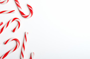 Blank frame with Christmas candy canes top view. New Year lollipops on white background. Winter holidays backdrop with copyspace. Xmas confection composition with decorative elements.