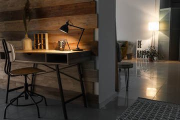 Workplace with glowing lamp in darkness