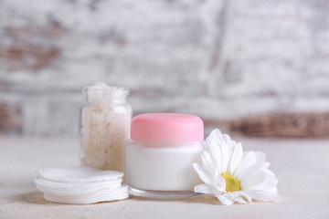 Obraz na płótnie Canvas Jar of cosmetics cream with sea salt and cotton sponges on light background