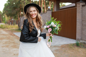 Fototapeta premium Beautiful young bride with bouquet of flowers on her wedding day outdoors