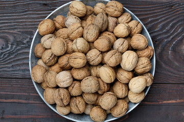An organic walnuts in a metal tray on a dark wooden table, close-up