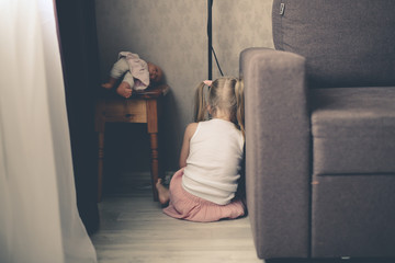 frustrated offended girl child hiding behind sofa